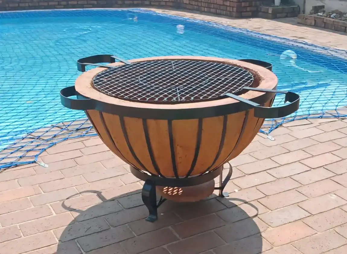 Round handcrafted braai boma beside a swimming pool
