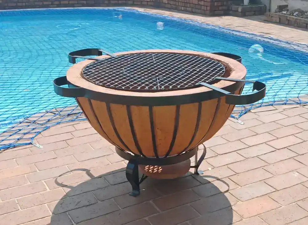 Round handcrafted braai boma beside a swimming pool